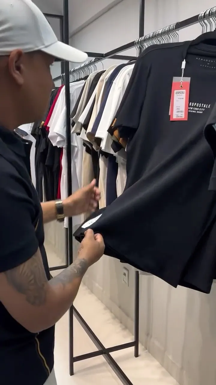 O Japa escolhendo camisetas Aeropostale na arara do showroom